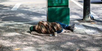 Homeless guy , sleeping on the street.